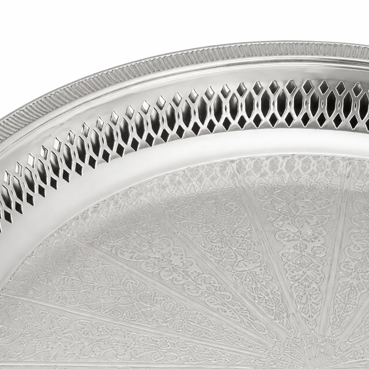 Detail van de gravure en opengewerkte rand van het zilverkleurige dienblad op pootjes