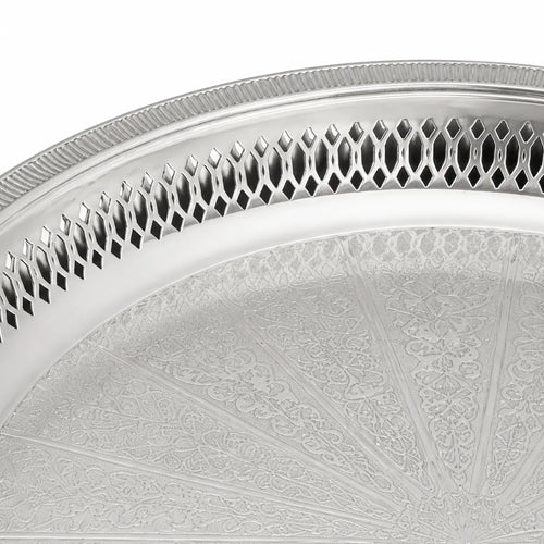 Detail van de gravure en opengewerkte rand van het zilverkleurige dienblad op pootjes