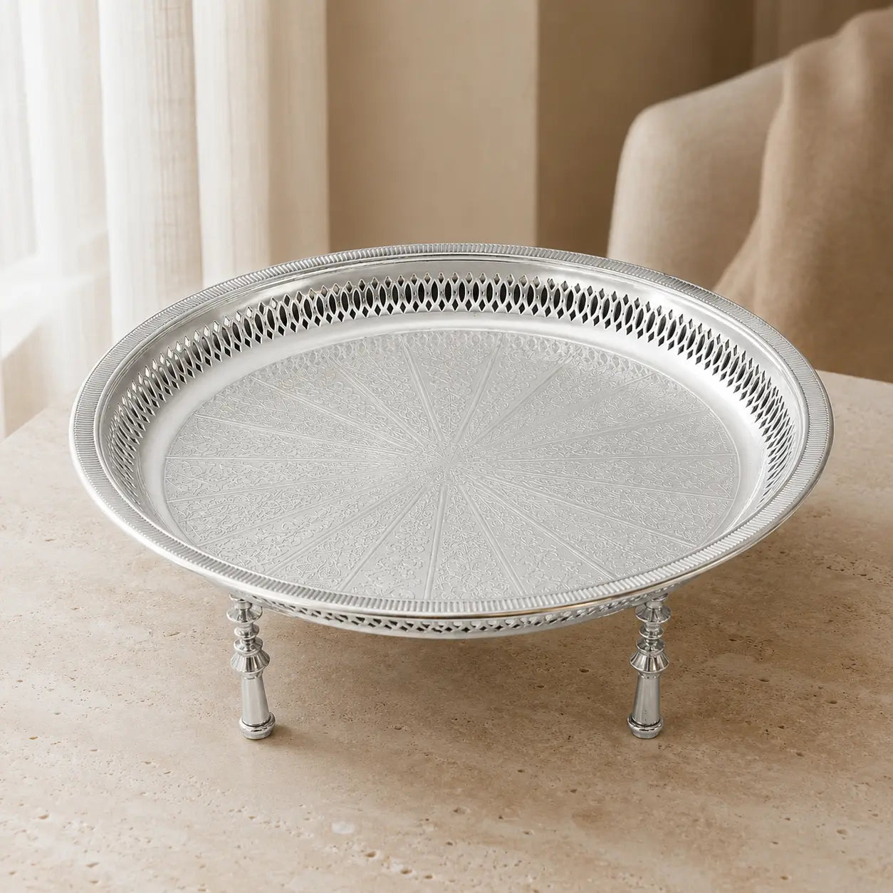 Zilverkleurig dienblad op pootjes op een lichte tafel in een beige interieur