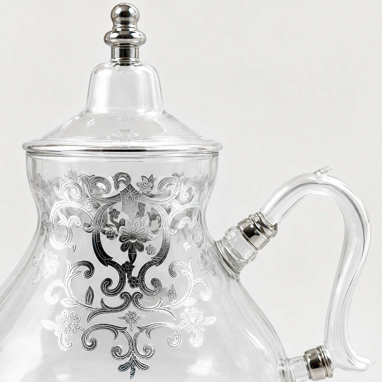 Detail van het zilverkleurige ornament en glazen handvat van theepot Ifran